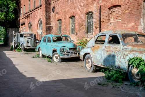 Preview: an Old rusty and abandoned retro car covered by green plants, outside