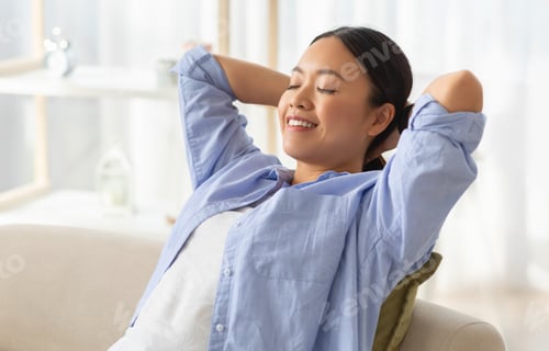 Preview: Overjoyed young asian woman relaxing on couch at home