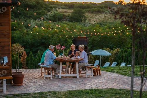 Preview: Cheerful family enjoying a family dinner outside at home during evening