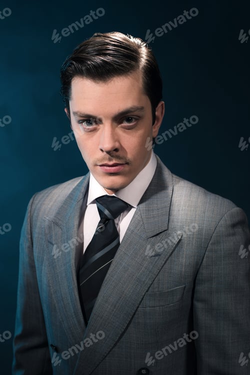 Preview: Retro 1940S Business Man In Suit And Tie Against Blue Wall.