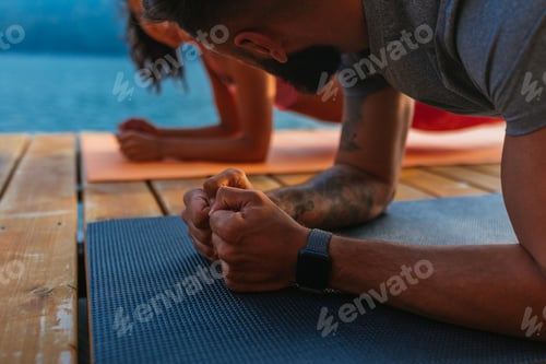 Preview: Couple doing a yoga near lake early in the morning