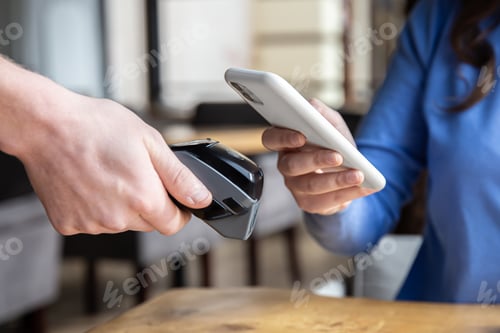 Preview: Paypass, male hands holding black pos terminal and female brings smartphone.