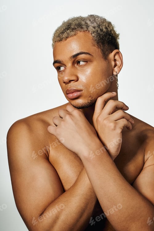 Preview: Striking pose of a young muscular man with dyed hair in studio setting