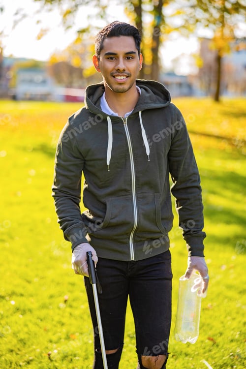 Preview: Confident young man cleaning park on sunny day