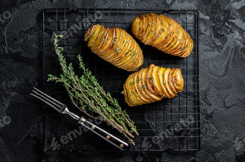 Preview: American traditional Homemade Hasselback Potato with Fresh Herbs. Black background. Top view
