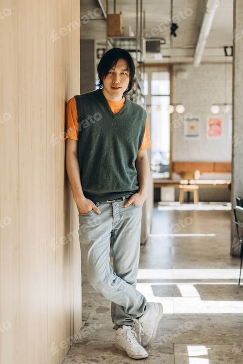 Preview: Young asian freelancer leaning against wall in coworking space