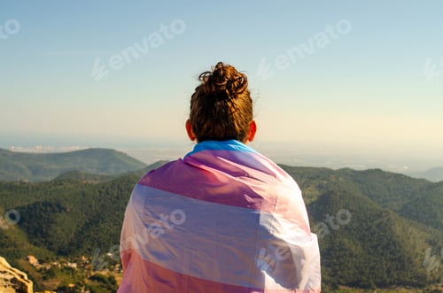 Preview: Young Long Hair Man With Topknot Back Sitting at Mountains Canyon Looking to Horizon in Nature with