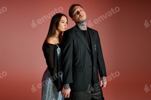 Preview: Young couple posing confidently in stylish outfits against a warm background in a creative studio