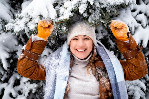 Preview: Playful woman plays with snow near fir tree branches in winter park