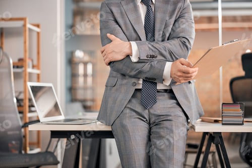 Preview: Businessman with documents sitting on the edge of office table