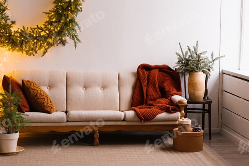 Preview: Sofa with a Blanket Near the Window, Branches of a Fir Tree in a Vase. Christmas Home Decoration