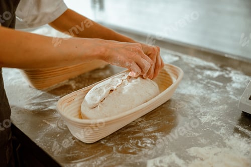Preview: Woman makes decor on raw bread loaf in ceramic dish in craft bakery