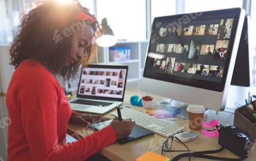 Preview: Young female graphic designer working on graphic tablet at desk in a modern office