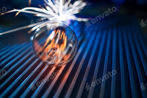 Preview: The incandescent lamp does not shine brightly and sparks fall on the metal surface in a dark room