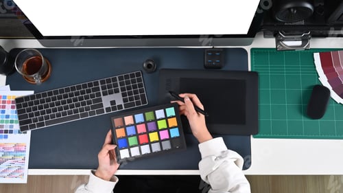 Preview: Young female designer working graphic tablet and color swatches at creative office.