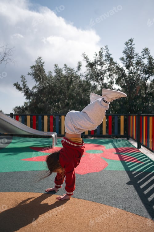 Preview: Child girl doing handstand on the outdoors playground. Funny active exercise