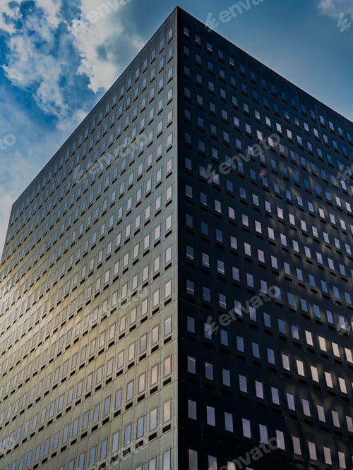 Preview: Modern high-rise office building with reflective windows against a partly cloudy sky