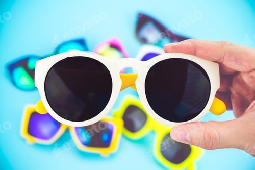 Preview: hand holding sunglasses with blur group of glasses at background