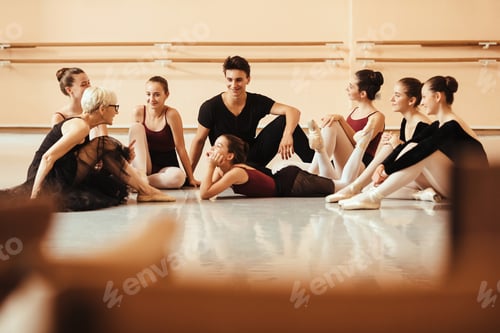 Preview: Ballet teacher talking with her students while relaxing on the floor at ballet studio.