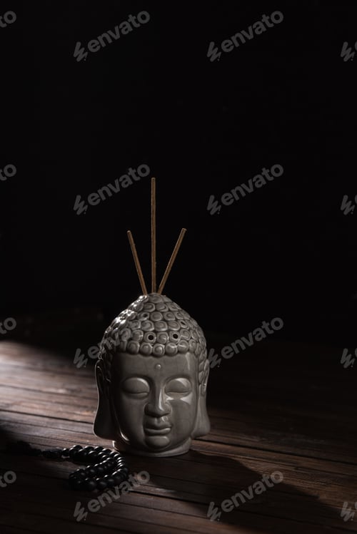 Preview: sculpture of buddha head with incense sticks on wooden table