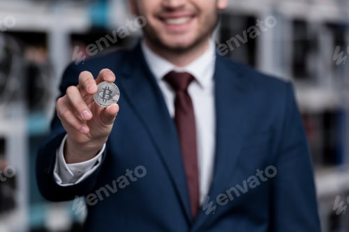 Preview: cropped shot of smiling businessman holding bitcoin at cryptocurrency mining farm