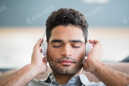 Preview: Man listening to music on headphones in living room