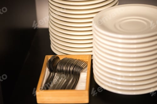 Preview: White plates in a row and forks in a box on a wooden surface