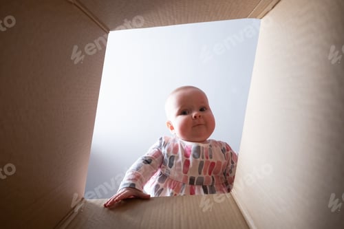 Preview: Happy baby into parcel cardboard box and smiling.