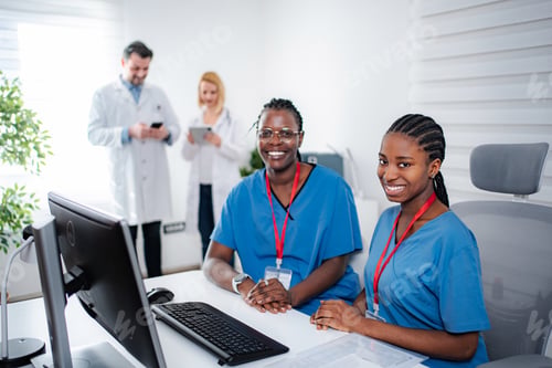 Preview: Two smiling female nurses working in hospital office