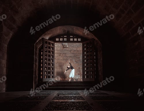 Preview: Graceful ballerina performing ballet position in dark passage