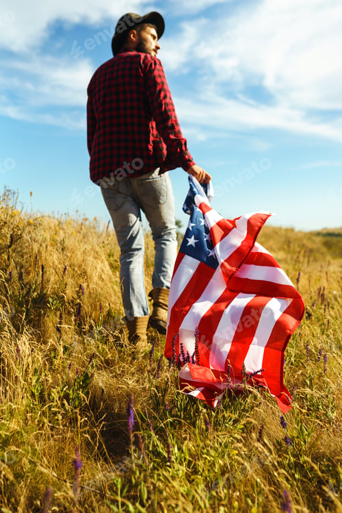 Preview: 4th of July. American Flag. Traveler with the flag of America. The man in a hat, a backpack, a shirt