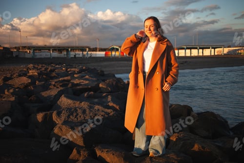 Preview: Woman enjoys seaside stroll at dusk.