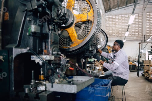 Preview: african black male worker working in heavy metal industry factory punching stamping steel machine