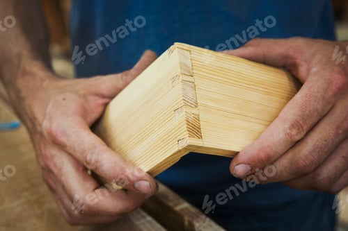 Preview: Close up of person working a boat-builder's workshop, joining together two pieces of wood.
