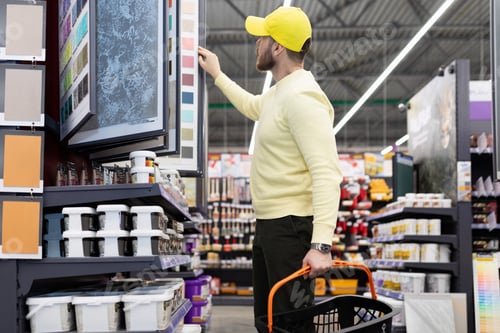 Preview: a man in a construction hypermarket chooses plaster for walls