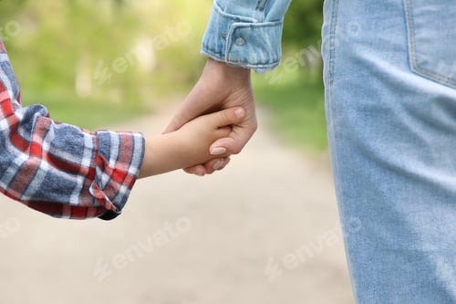 Preview: Little child holding hands with his mother outdoors, closeup. Family weekend