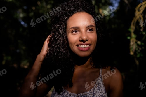 Preview: portrait outdoors of a beautiful young afro american woman smiling at sunset. Black background