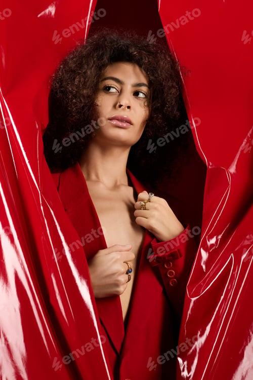 Preview: Curly young woman in a stylish red outfit celebrates Valentines Day in the studio