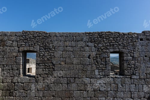 Preview: Castle of Belmonte with stone walls and engravings under a blue sky and sunlight in Portugal