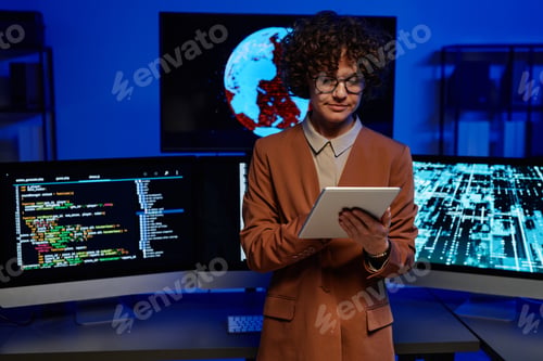 Preview: Young serious female programmer using tablet against computers