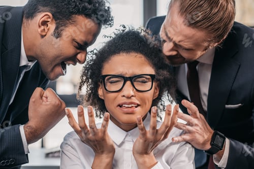 Preview: two emotional businessmen in formalwear screaming on businesswoman in office, multicultural business