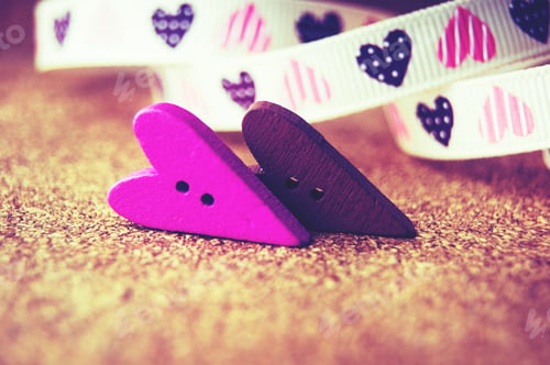 Preview: Two wooden hearts on a wooden background. white ribbon with hearts