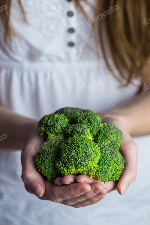 Preview: Woman showing fresh green brocolli in close up