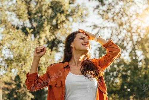 Preview: Low-angle portrait of happy young woman outdoors in early autumn