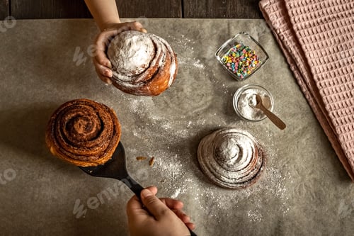 Preview: Children's hand takes a freshly baked cinnamon bun.
