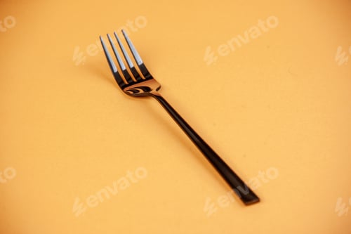 Preview: Front view of shiny stainless metal fork lying on peach color background with free space