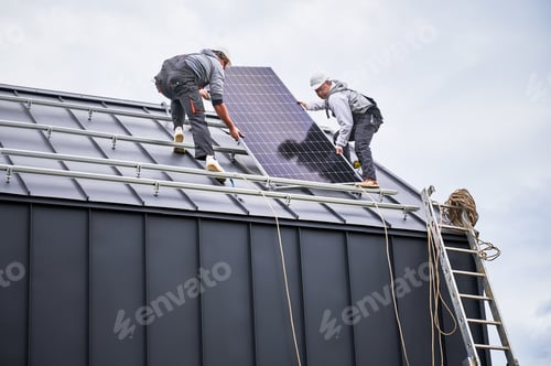 Preview: Technicians carrying photovoltaic solar module while installing solar panel system on roof of house