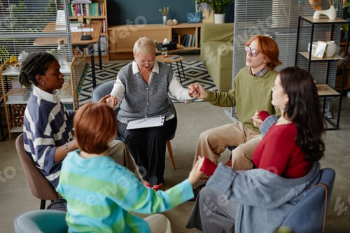 Preview: Diverse Group of Adults Sitting in Circle Holding Hands during Support Meeting