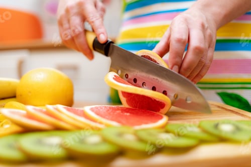 Preview: Women's hands Housewives cut with a knife fresh grapefruit on th