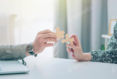 Preview: The hands of business partners hold the puzzle elements in the office above the desktop.